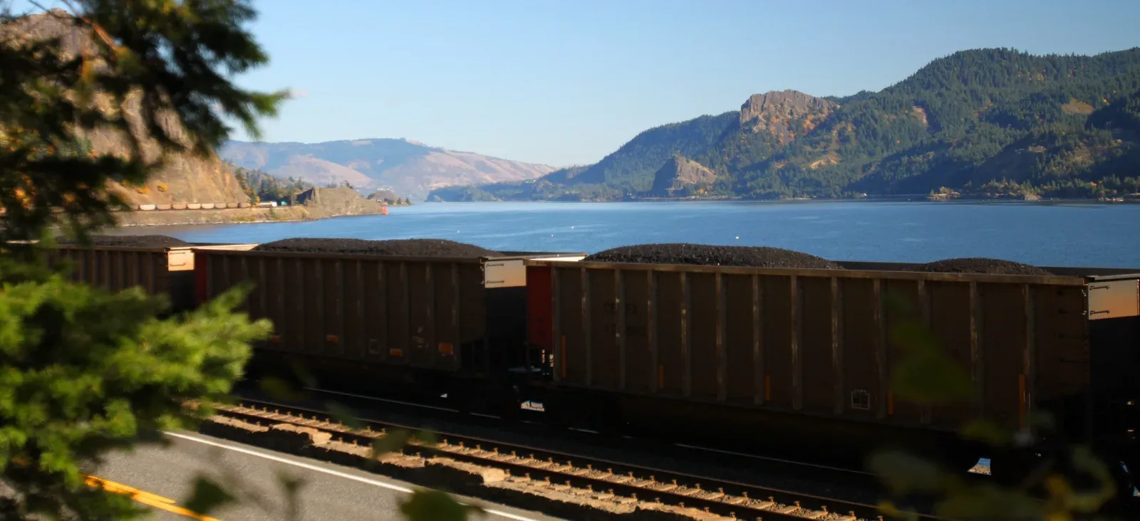 A open-top coal train thunders alongside Washington State Route 14 in the Columbia Gorge. Photo by Daniel Dancer.