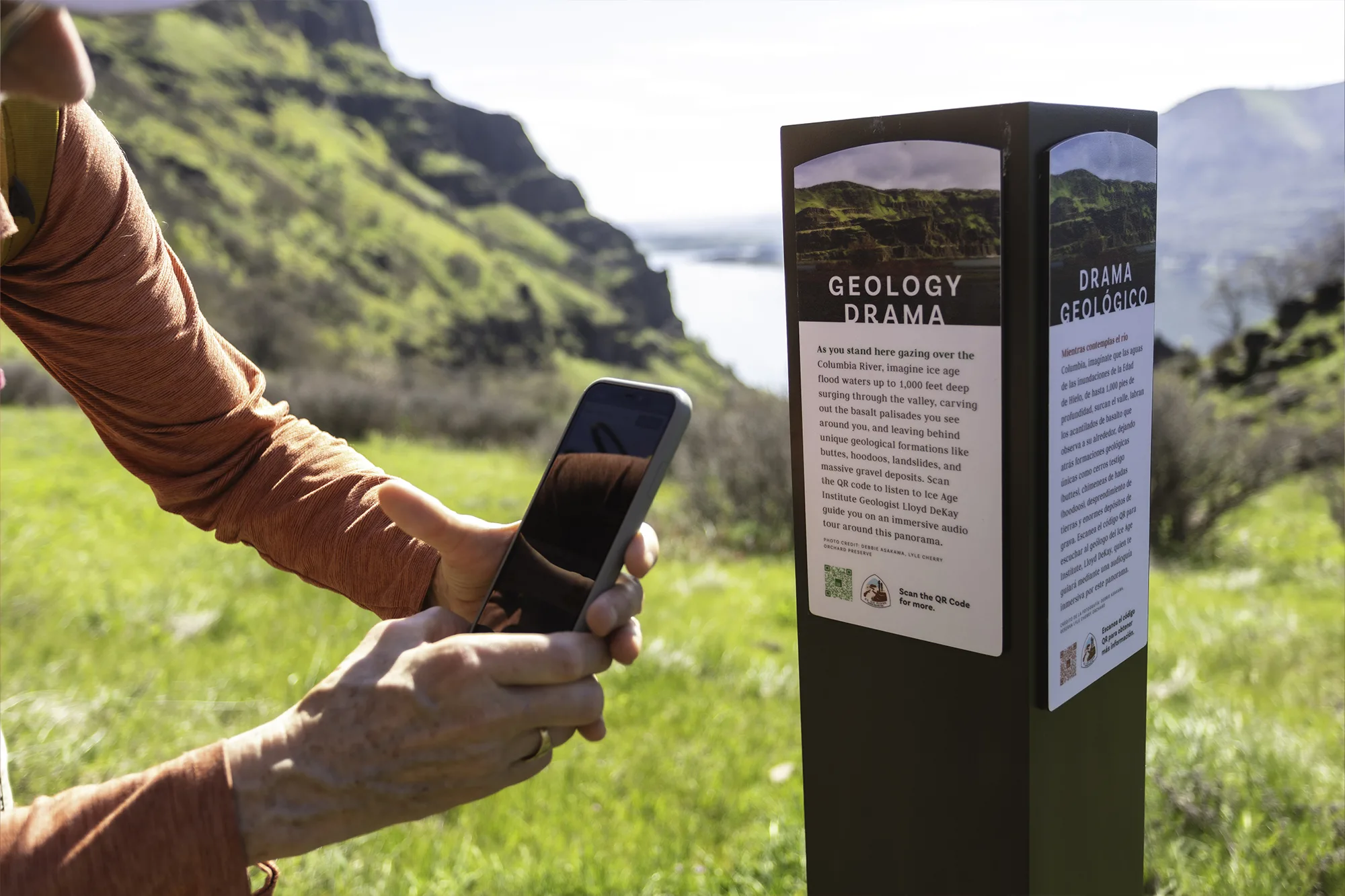 A hiker at Lyle Cherry Orchard scans a QR code with their phone. Photo by Monique Trevett.